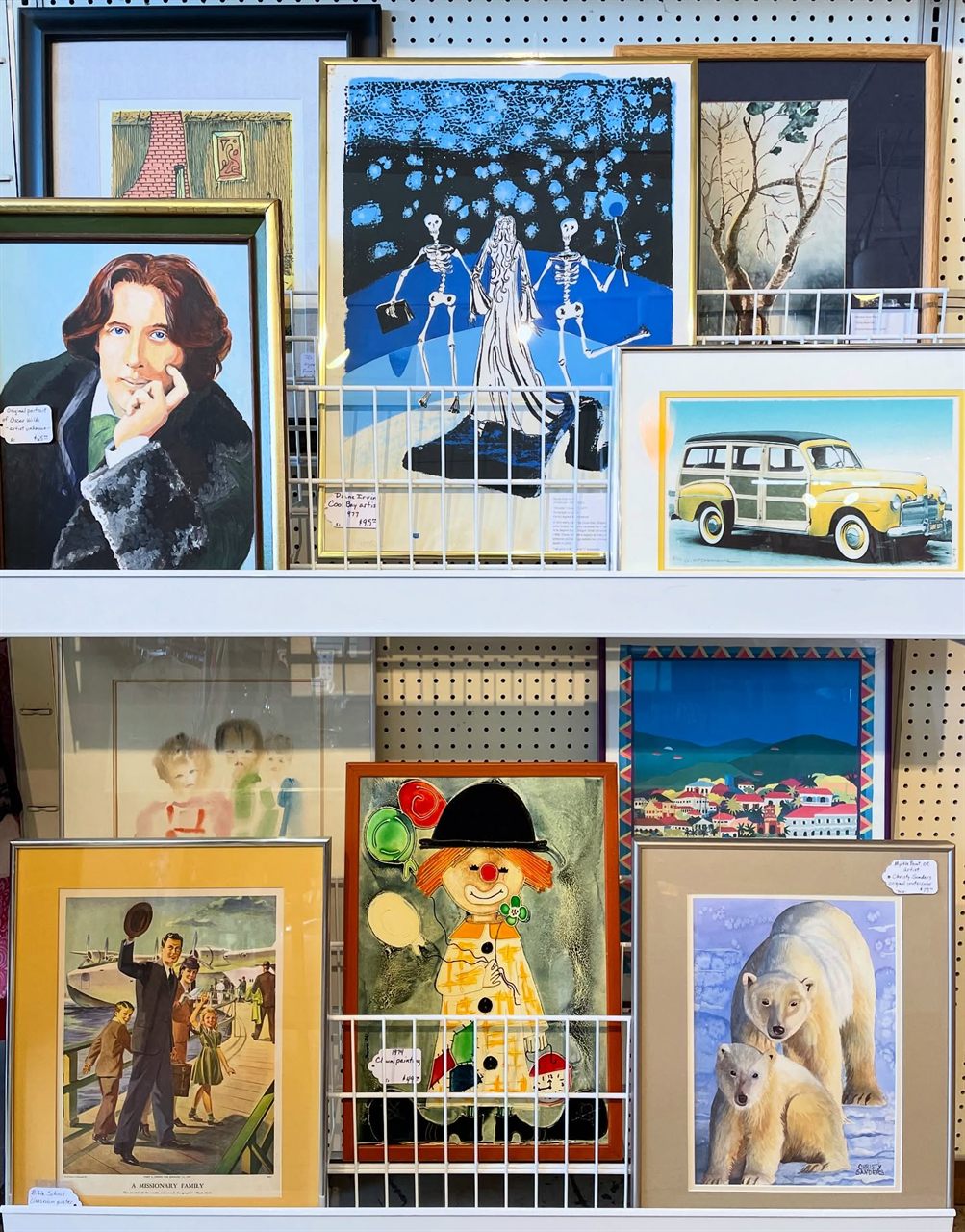 Wall of framed paintings and prints including work by local artists