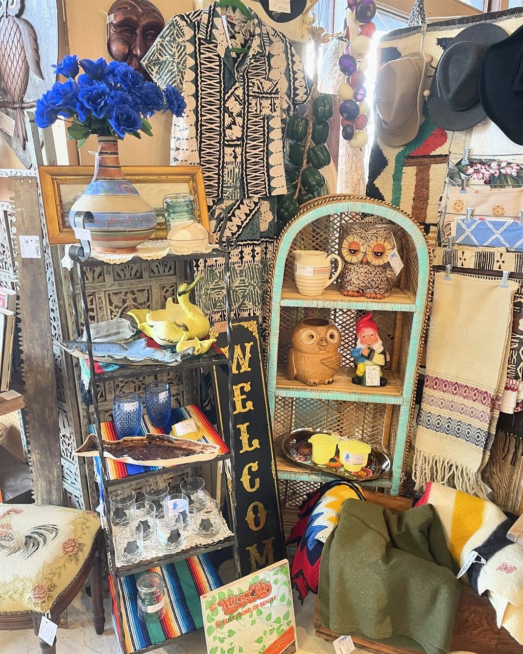 Booth with blue flowers, owl figurines on a teal etagere, and Southwestern blankets