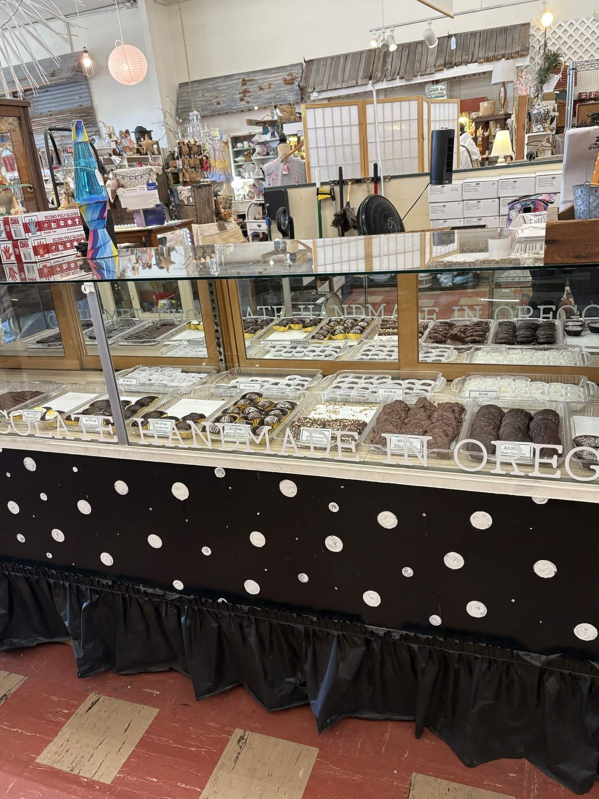 Glass display case of gourmet chocolate truffles and clusters labeled handmade in Oregon