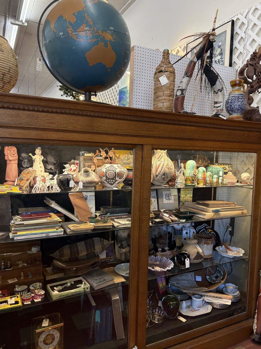 Oak cabinet topped with a vintage world globe and filled with Southwestern pottery and collectibles