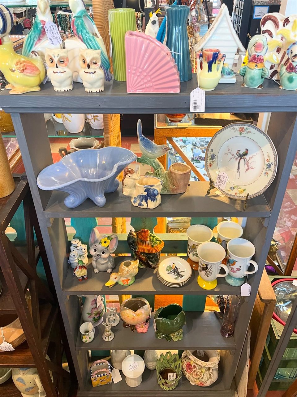 Shelves of vintage pottery, owl figurines, and bird planters