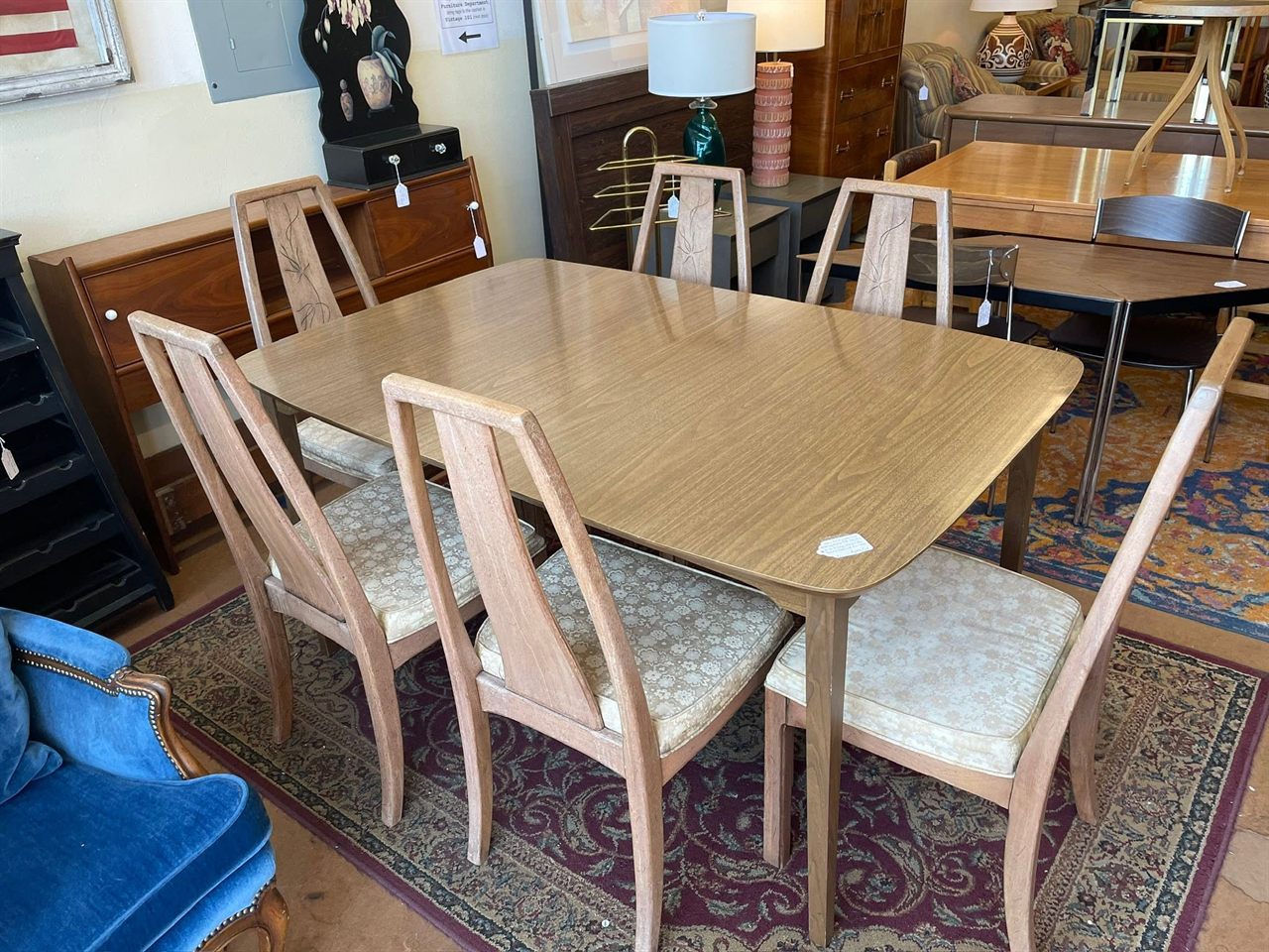 Mid-century light wood dining table with six matching chairs on an oriental rug