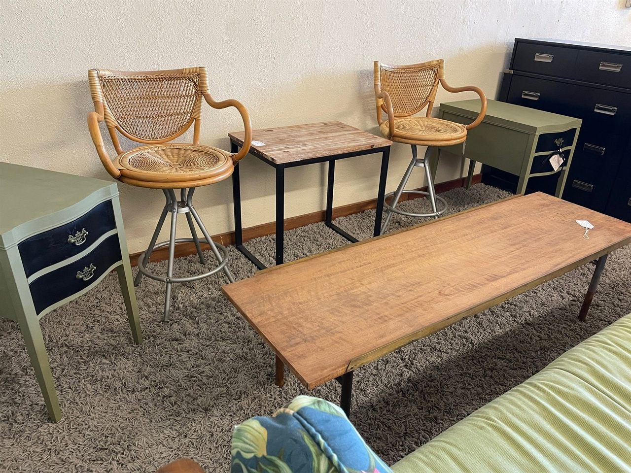 Furniture vignette with rattan swivel stools, a wood coffee table, and a painted console