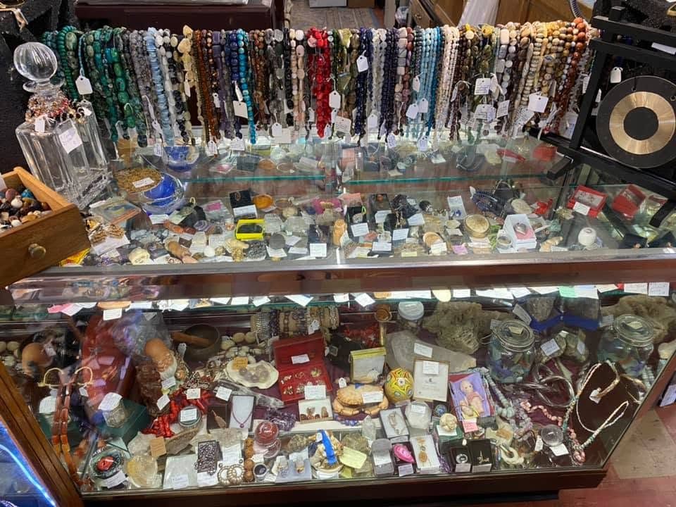 Glass case with strands of gemstone beads, crystals, and minerals