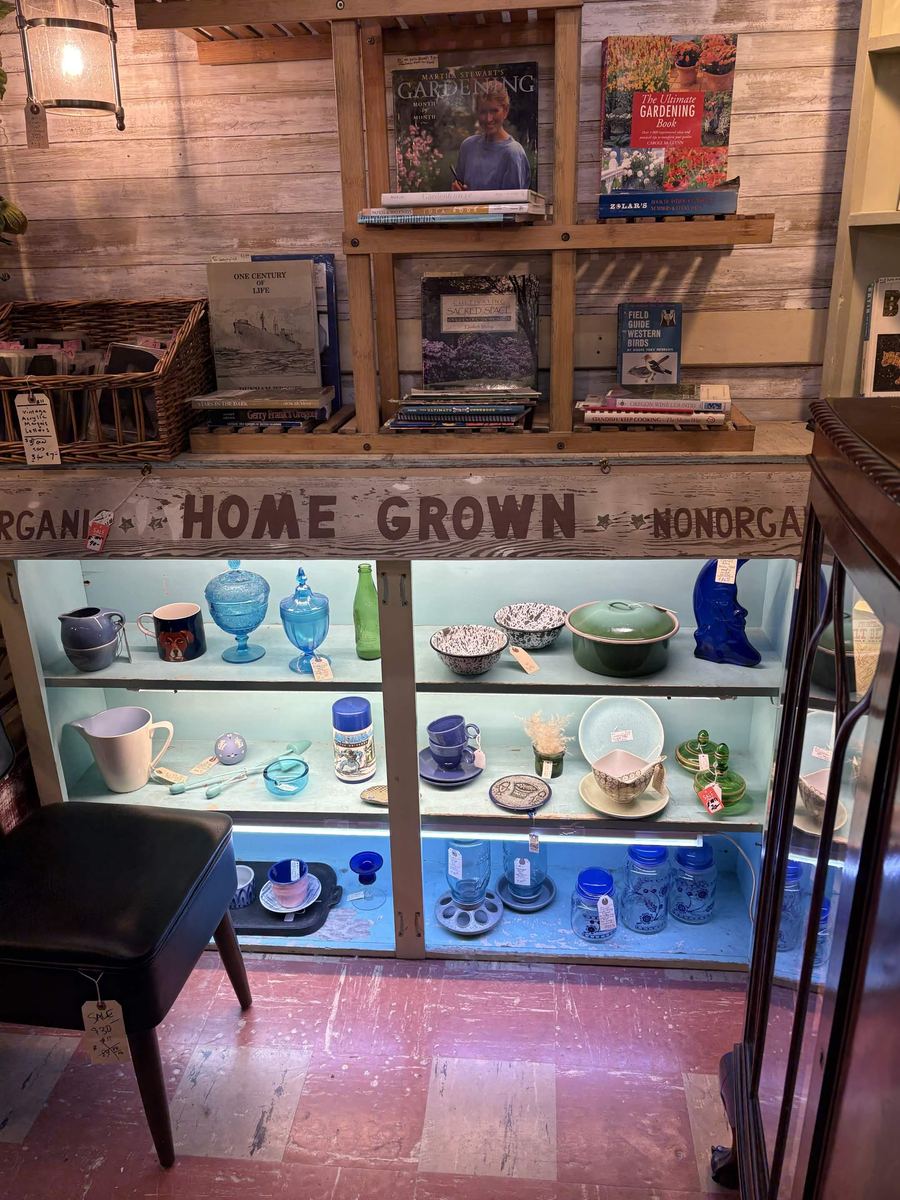 Glass case of blue and green vintage kitchenware under a hand lettered Home Grown sign