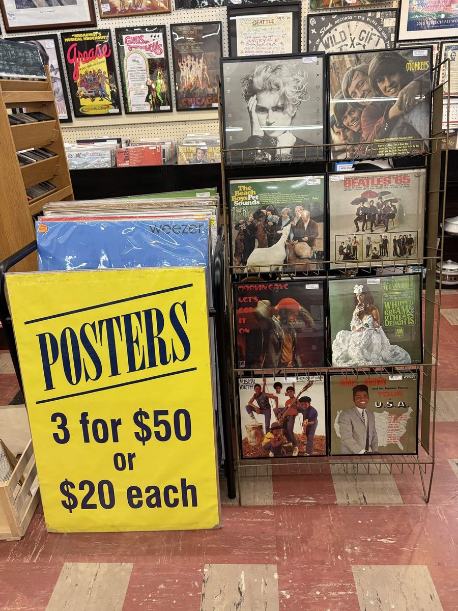 Framed album covers including Madonna, the Monkees, and Pet Sounds beside a posters sign